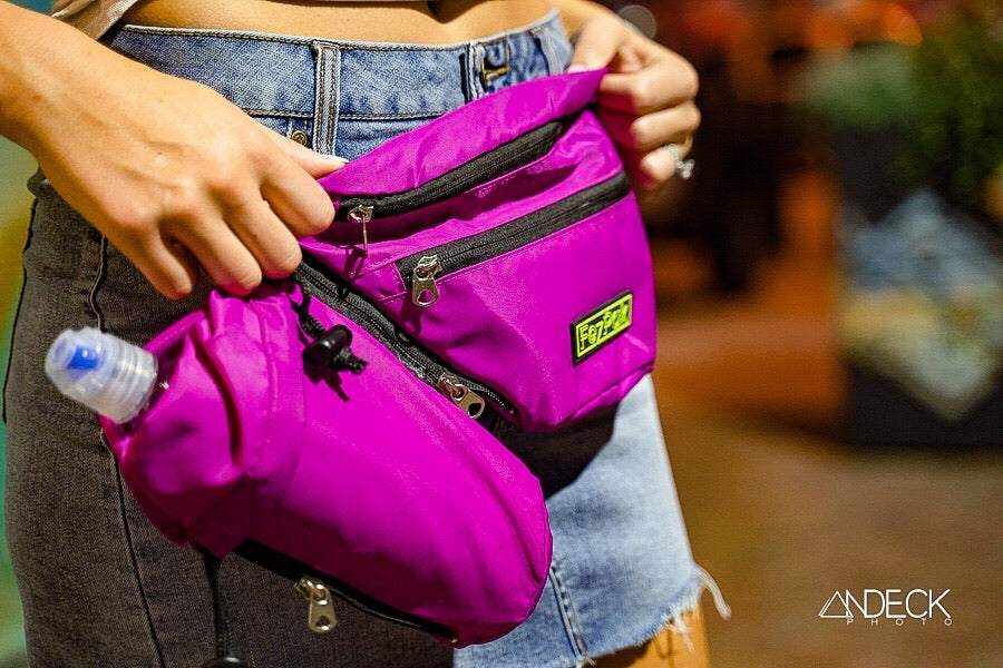 FezPak customizable purple fanny pack with detachable bottle holder and multiple zip pockets worn with denim shorts