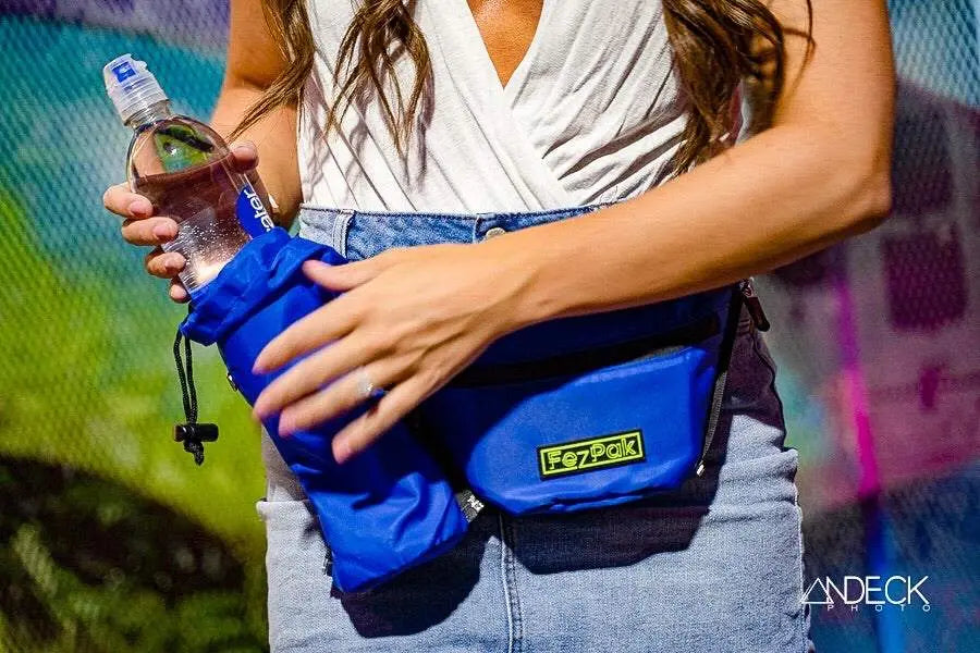 Woman wearing blue FezPak customizable fanny pack with attachable bottle holder holding a water bottle