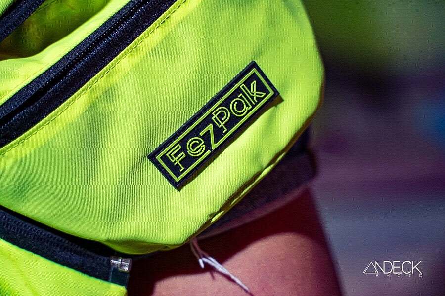 Close-up of neon green FezPak customizable flat design fanny pack with black zipper and logo patch