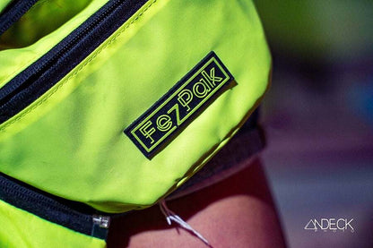 FezPak customizable flat design fanny pack in neon yellow with distinctive branding, featuring water-resistant nylon material and multiple pockets.